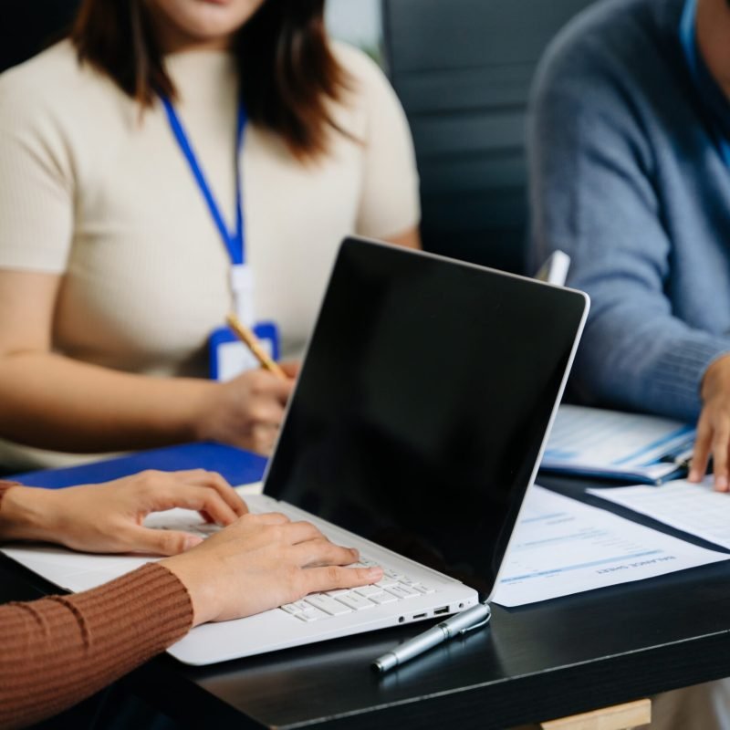 Young professionals or students working together using a laptop and reports. Perfect for themes of teamwork, planning, education, research, and collaboration.